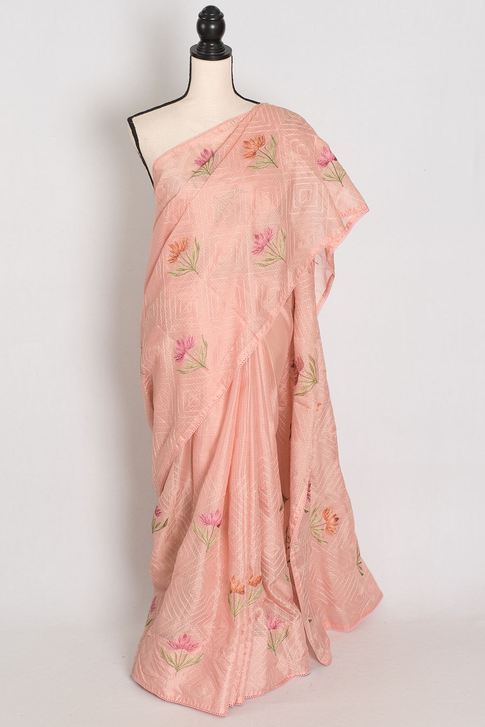 Pastel peach Kota silk saree styled elegantly on a mannequin, showcasing its light-as-air fluid drape and floral embroidery.