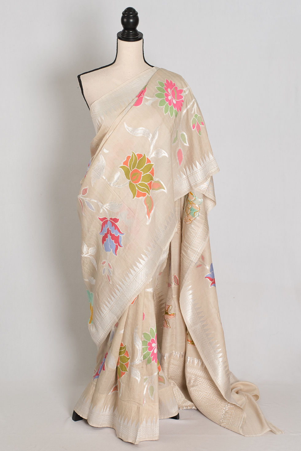 Warm beige Tussar Georgette Banarasi saree with large pink, blue, and orange Minakari floral motifs and silver border.