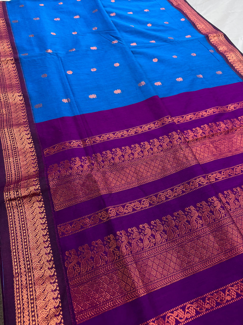 Ankhi bright blue and purple blended cotton Gadwal saree highlighting the intricate copper peacock zari motifs on the pallu.
