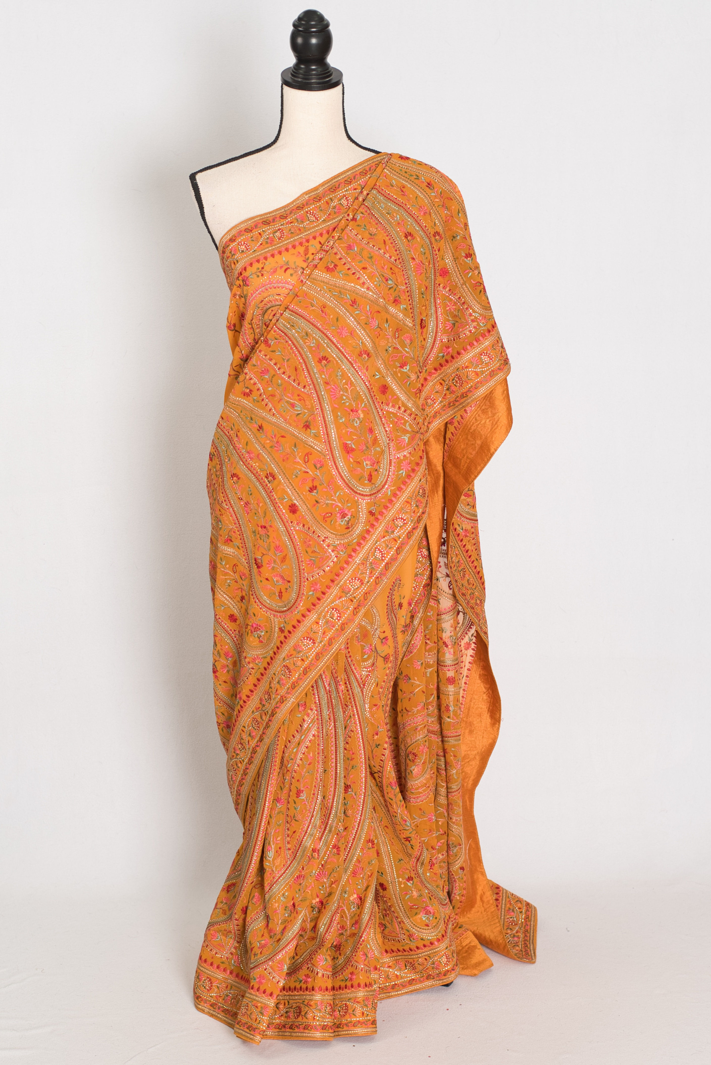 Turmeric yellow georgette partywear saree on a mannequin showing all-over Kashmiri machine embroidery jaal work.