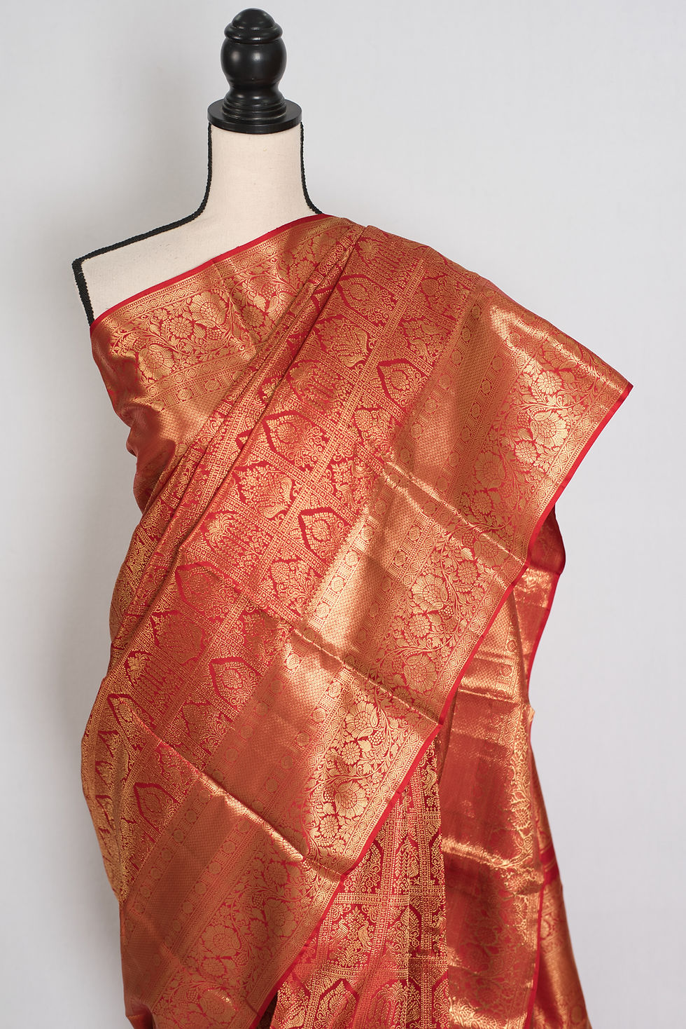 Thumbnail: Premium red and gold bridal Kanjivaram silk saree with heavy gold zari brocade patterns draped on a mannequin.