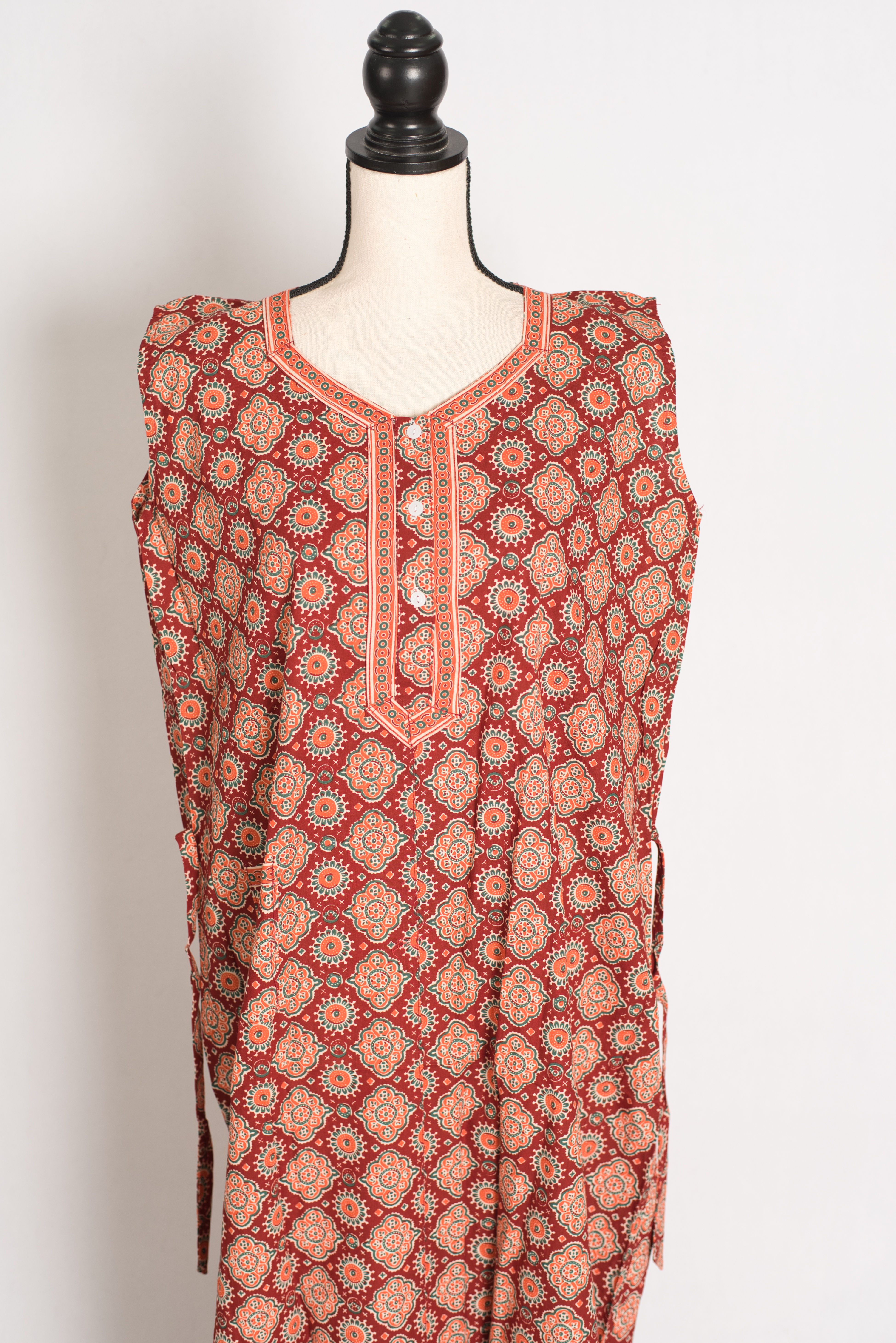 Close-up of the sleeveless design, front-buttoned neckline border, and intricate Kalamkari patterns on a red women's nighty