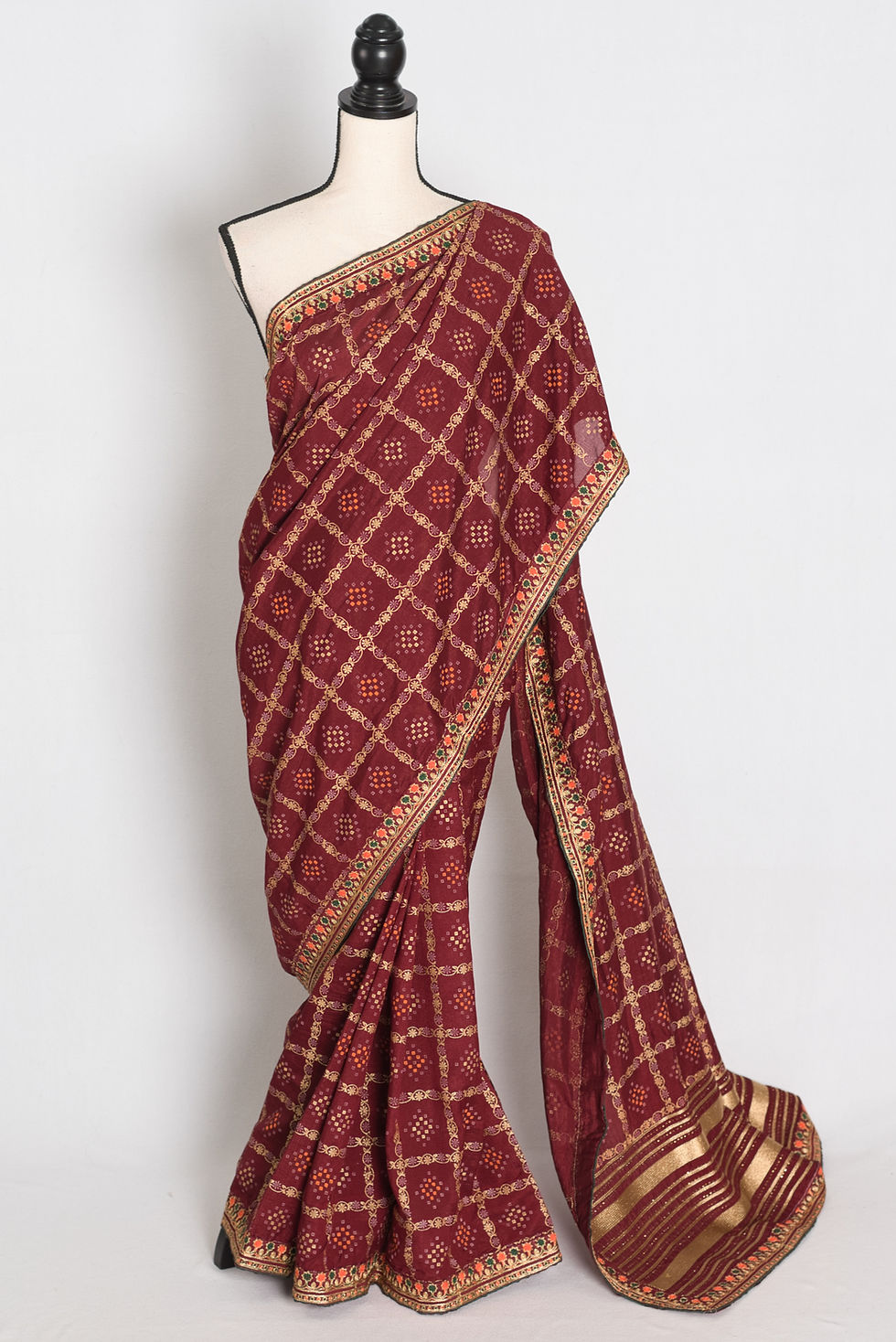 maroon semi Tussar silk saree in a traditional Gharchola gold print pattern on a mannequin.