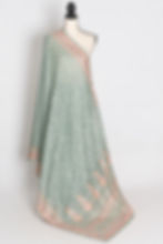 teal green crushed georgette saree with all-over intricate floral machine embroidery and pink border on a mannequin.