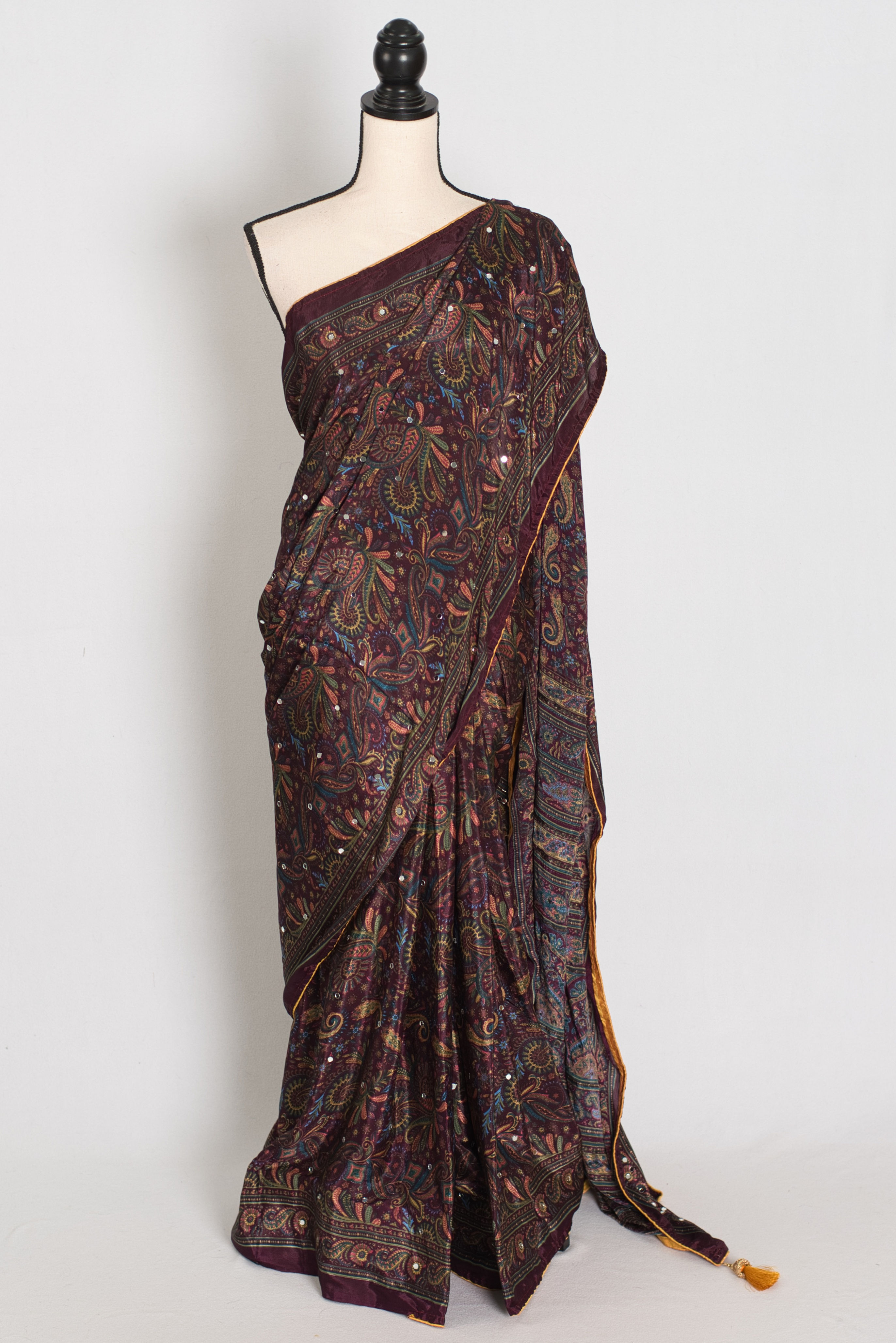 Deep purple semi modal silk partywear saree draped on a mannequin, showcasing Kalamkari paisley printing, mirror work.