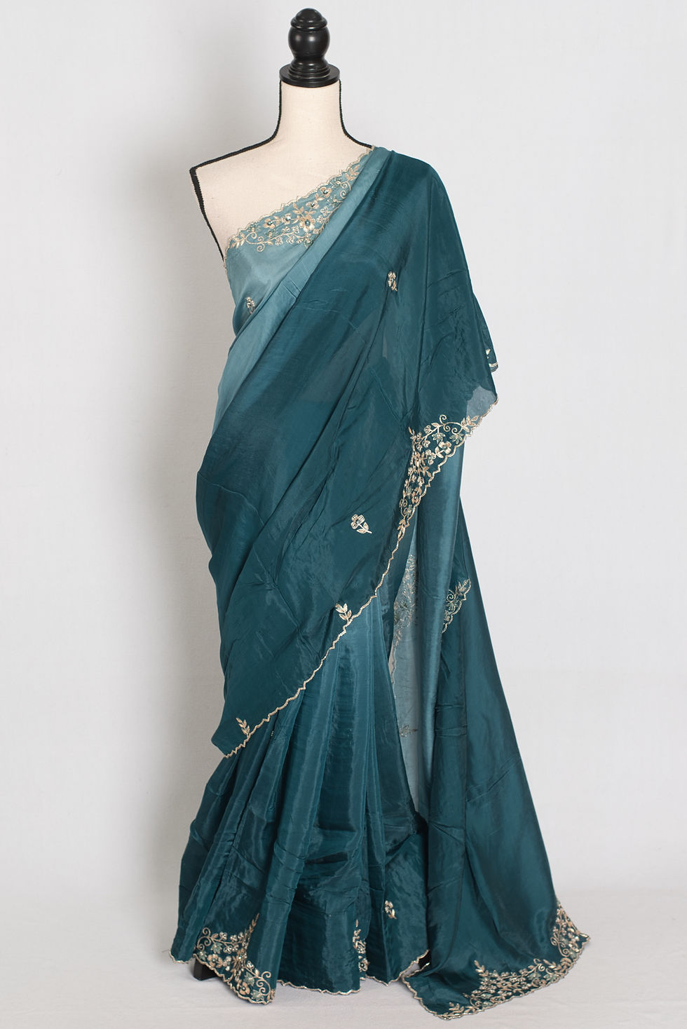 Front full-length view of the teal green shaded soft organza partywear saree draped on a mannequin.