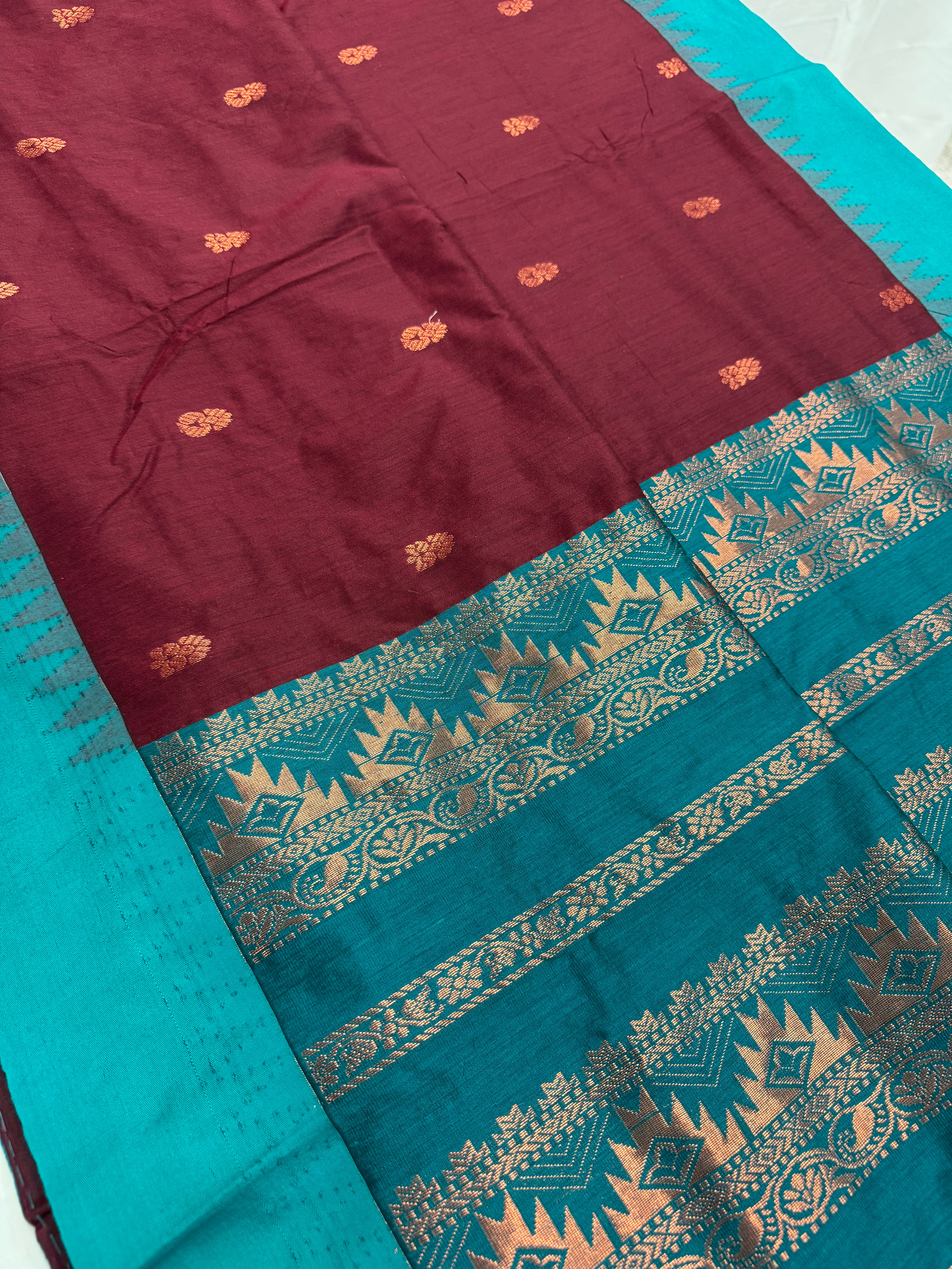 Dark brown blended cotton saree with sea green contrast border and copper zari temple motifs.
