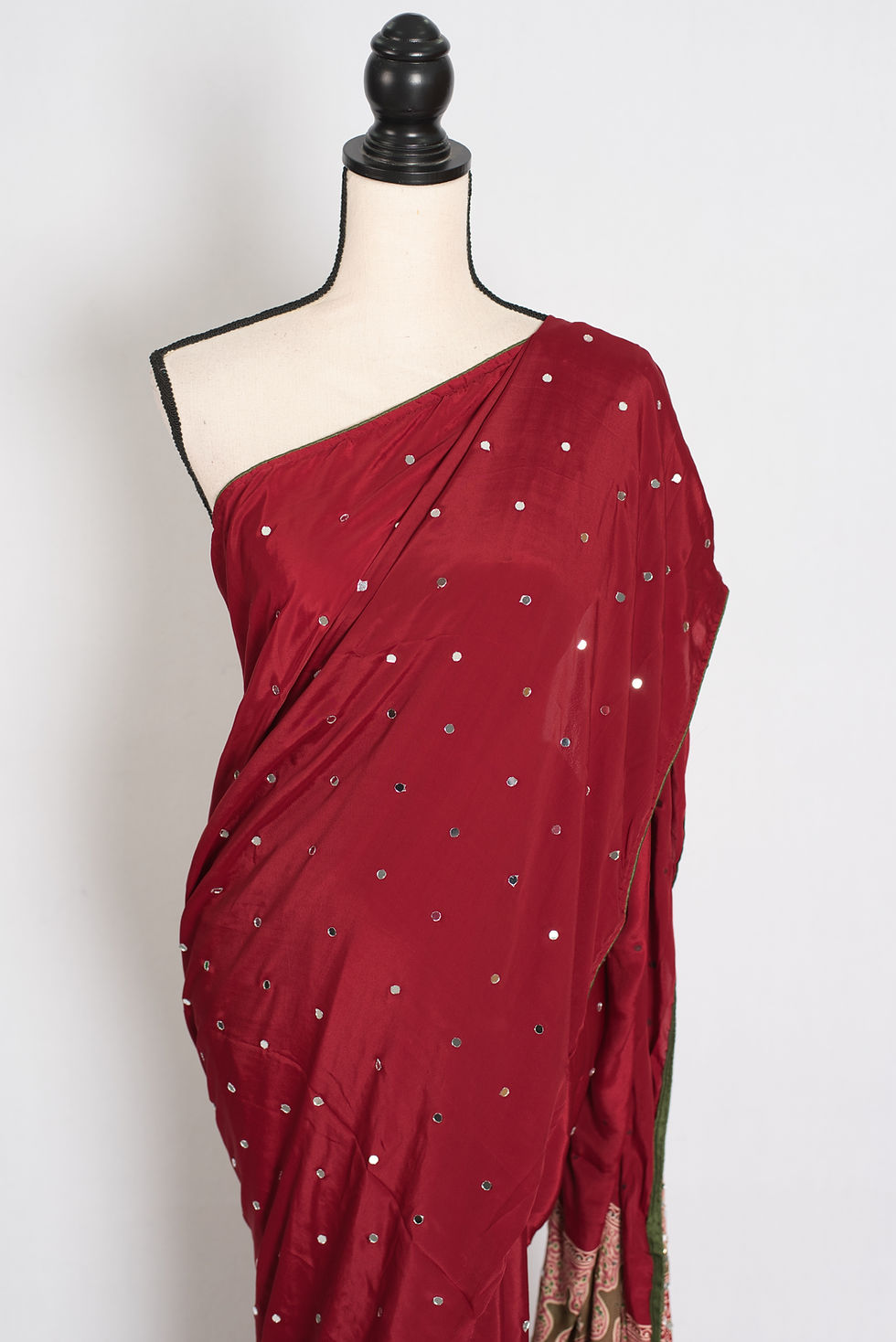 Thumbnail: Brick red semi modal silk partywear saree draped on a mannequin showcasing all-over hand pasted mirror work