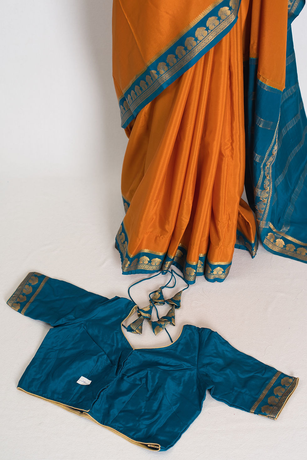 orange and turquoise pure mysore silk saree draped on a mannequin showcasing the soft 85 gms crepe drape.