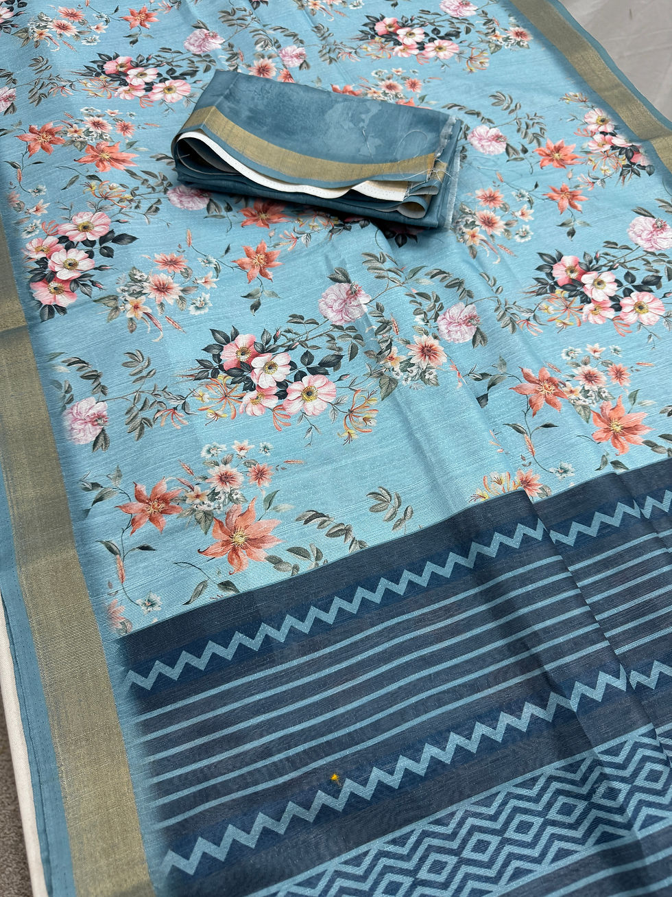 Afrin collection: Sky blue floral printed semi tussar saree with navy blue geometric pallu, budget-friendly gifting saree.