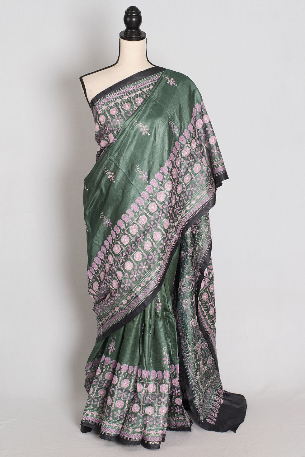Hunter green and black Tussar silk saree with soft pink hand-embroidered Kantha stitch floral borders draped on a mannequin.
