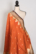 Thumbnail: Bina rust orange and coffee brown handwoven Banarasi silk saree with golden zari temple border on a mannequin.