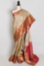 Mud white semi silk Kanjivaram saree with a brick red contrast skirt border and gold zari details draped on a mannequin.