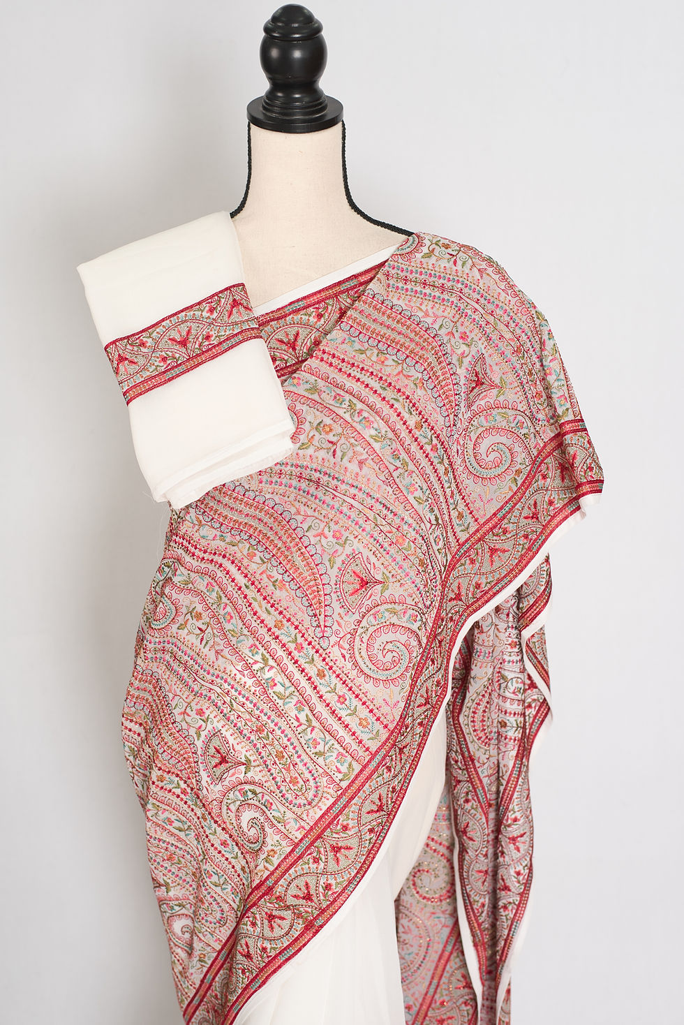 Thumbnail: White and red georgette partywear saree on a mannequin displaying all-over multicolor Kashmiri machine embroidery jaal.