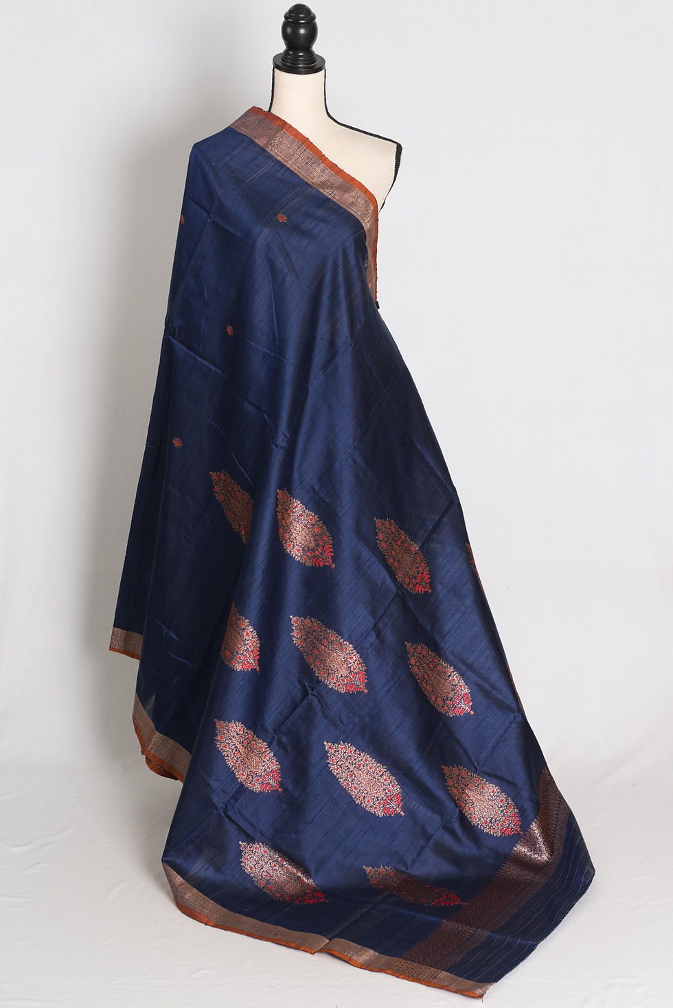 Midnight blue pure raw silk Tussar Banarasi saree featuring rust brown borders, bronze zari, red Minakari leaf bootis.