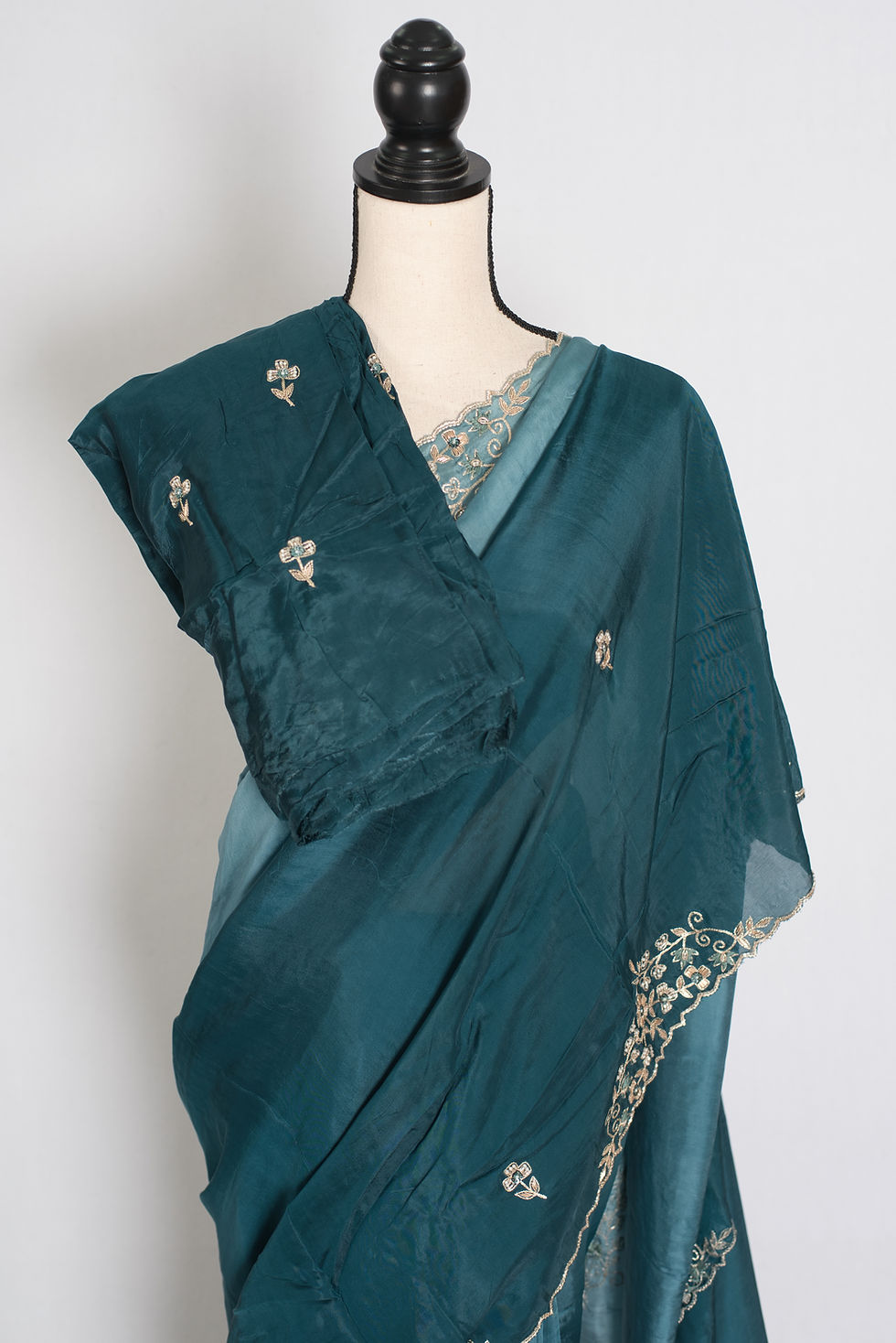 Front full-length view of the teal green shaded soft organza partywear saree draped on a mannequin.
