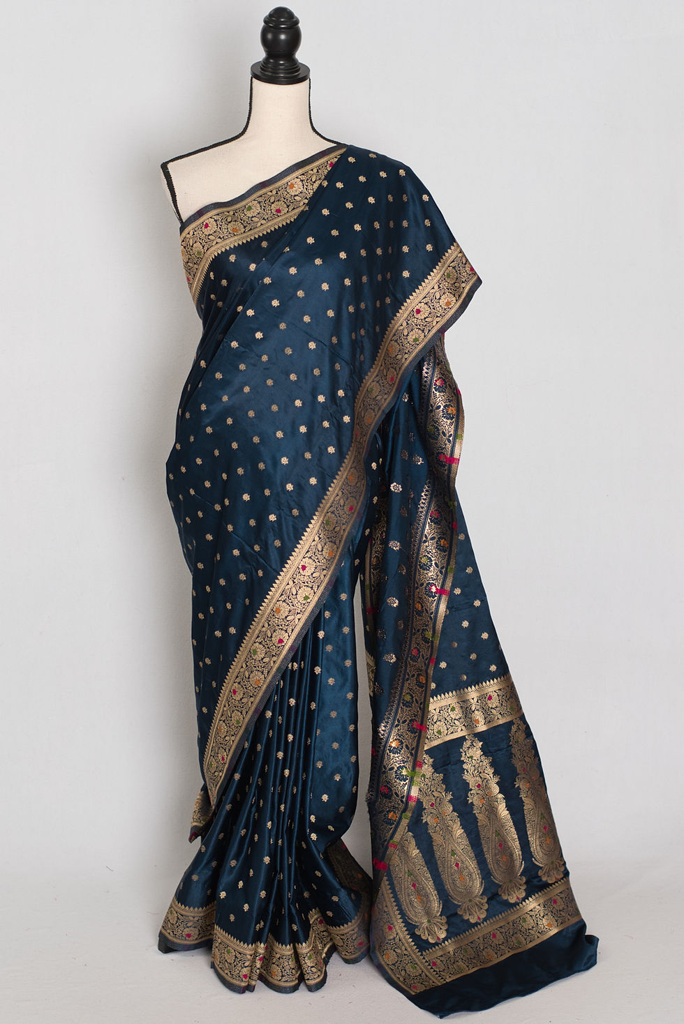 Midnight blue semi mashru Banarasi saree draped on a mannequin displaying its all-over gold zari butis.