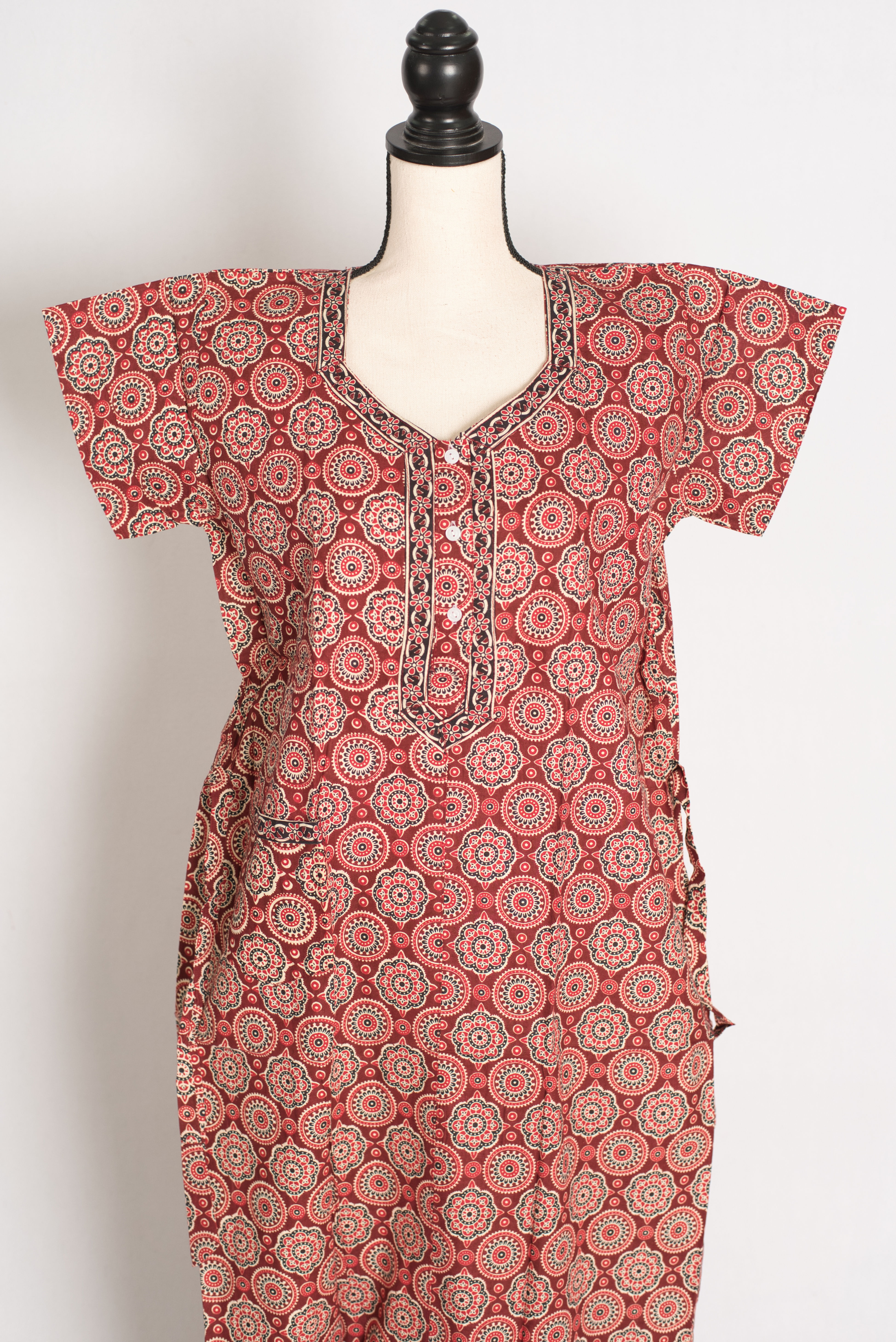 Close-up of the front-buttoned V-neckline and intricate traditional block print patterns on a brick red 100% cotton nightgown
