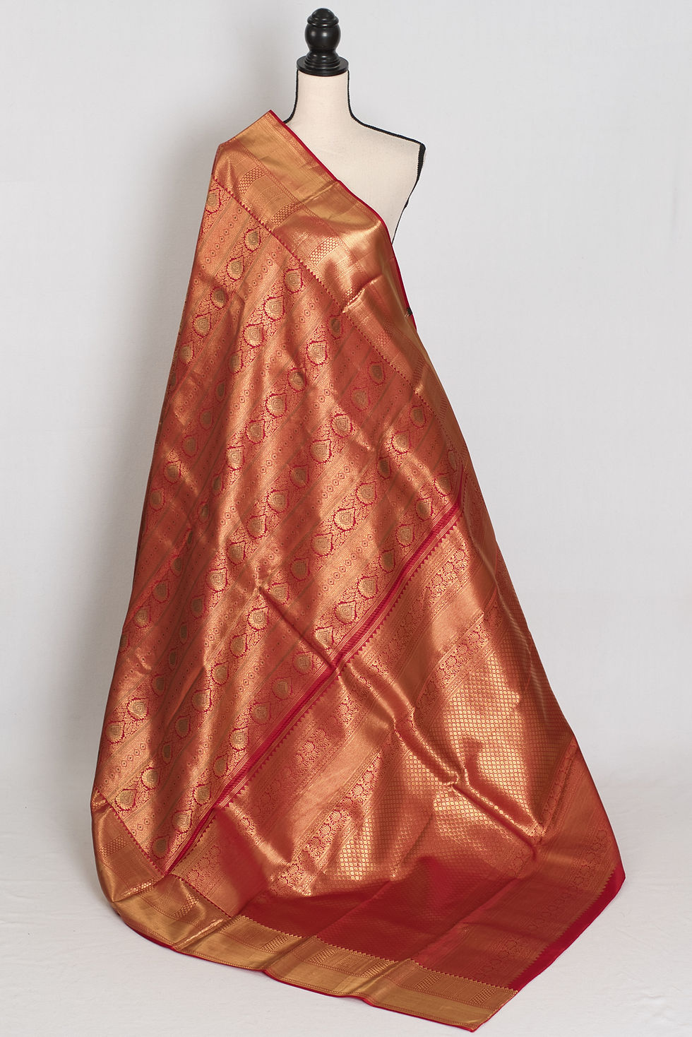 Premium dark red and gold bridal Kanjivaram silk saree with all-over gold zari brocade patterns draped on a mannequin.