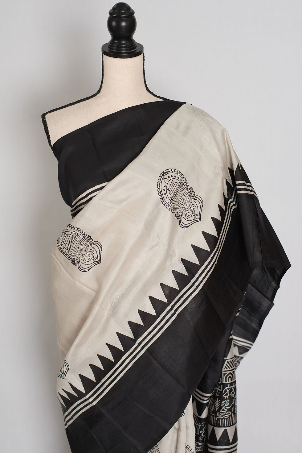Thumbnail: Off-white and black Murshidabad silk saree with Kalamkari-style mask prints and a geometric temple border on a mannequin.