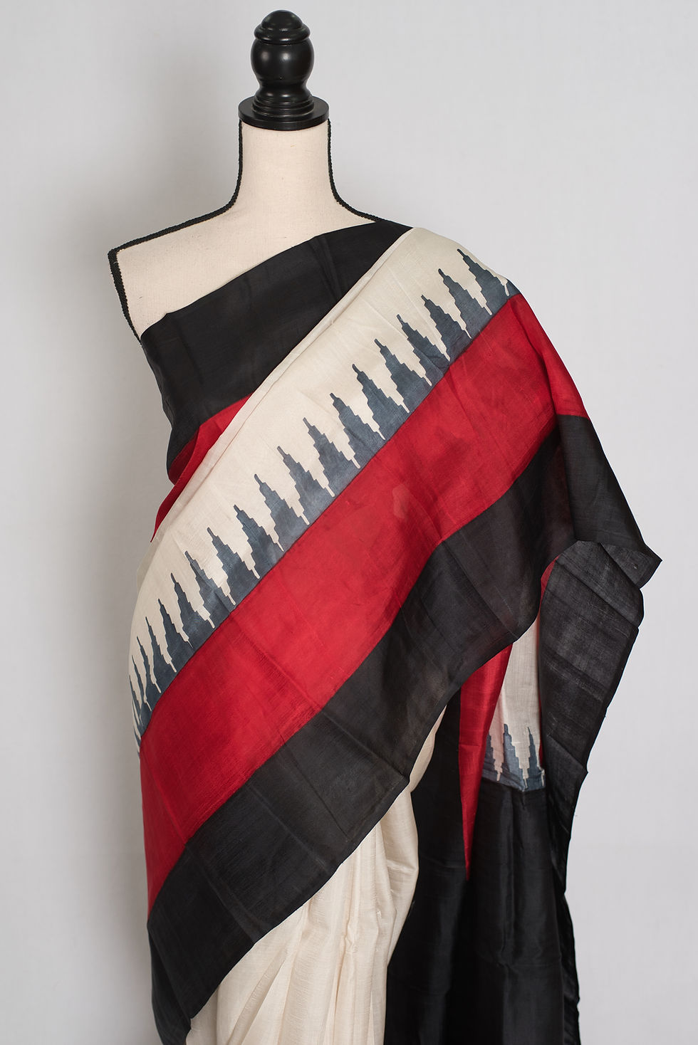 Thumbnail: Mohita white, black, and red Murshidabad silk saree with a geometric temple border design draped beautifully on a mannequin.