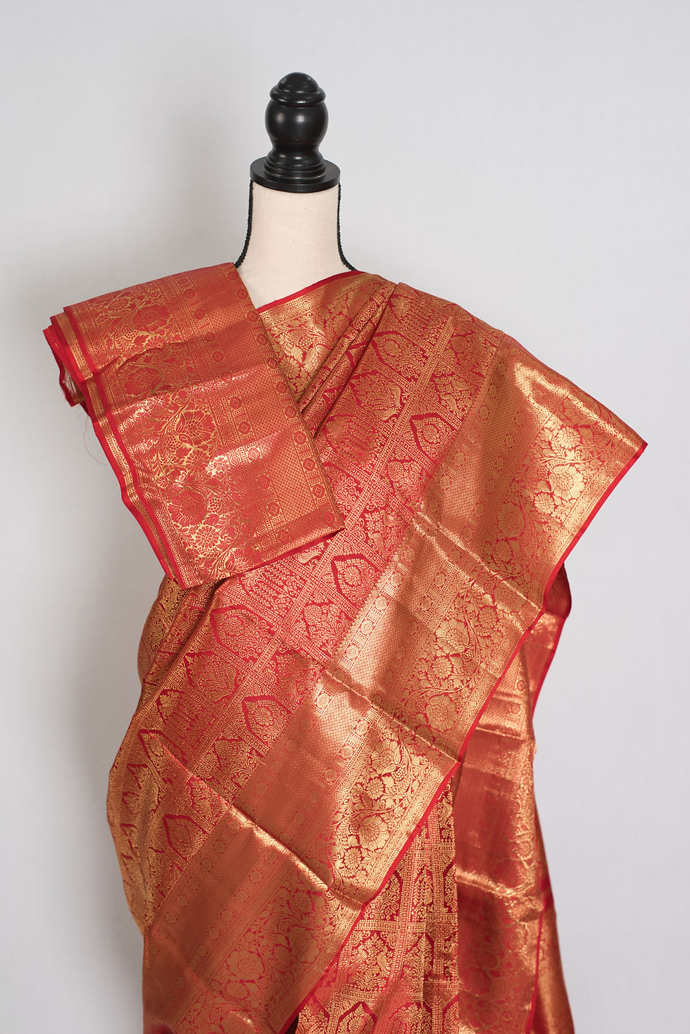 Thumbnail: Premium red and gold bridal Kanjivaram silk saree with heavy gold zari brocade patterns draped on a mannequin.