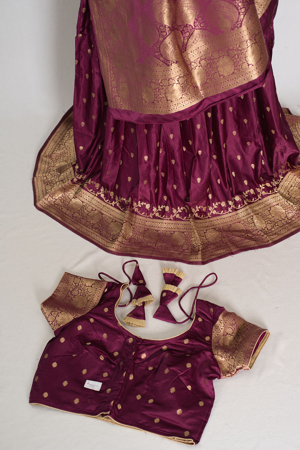 Stitched purple silk blouse with gold butti bootis, sweetheart neckline, and decorative latkan tassels matching the lehenga.