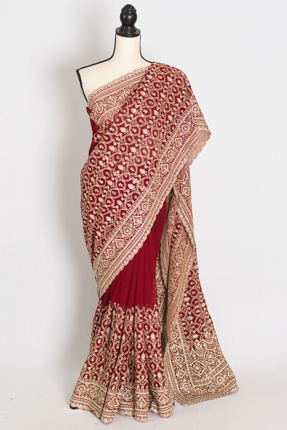Maroon and gold georgette bridal saree beautifully draped on a mannequin all-over heavy gold machine thread embroidery jaal.