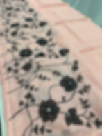 Soft peach and black semi kota silk saree with floral appliqué work and black machine embroidery.