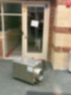 An industrial fan sits in the vestibule, a dehumidifier is visible through the office door, where we also see carpet is removed and the floor covered with plastic and tape.
