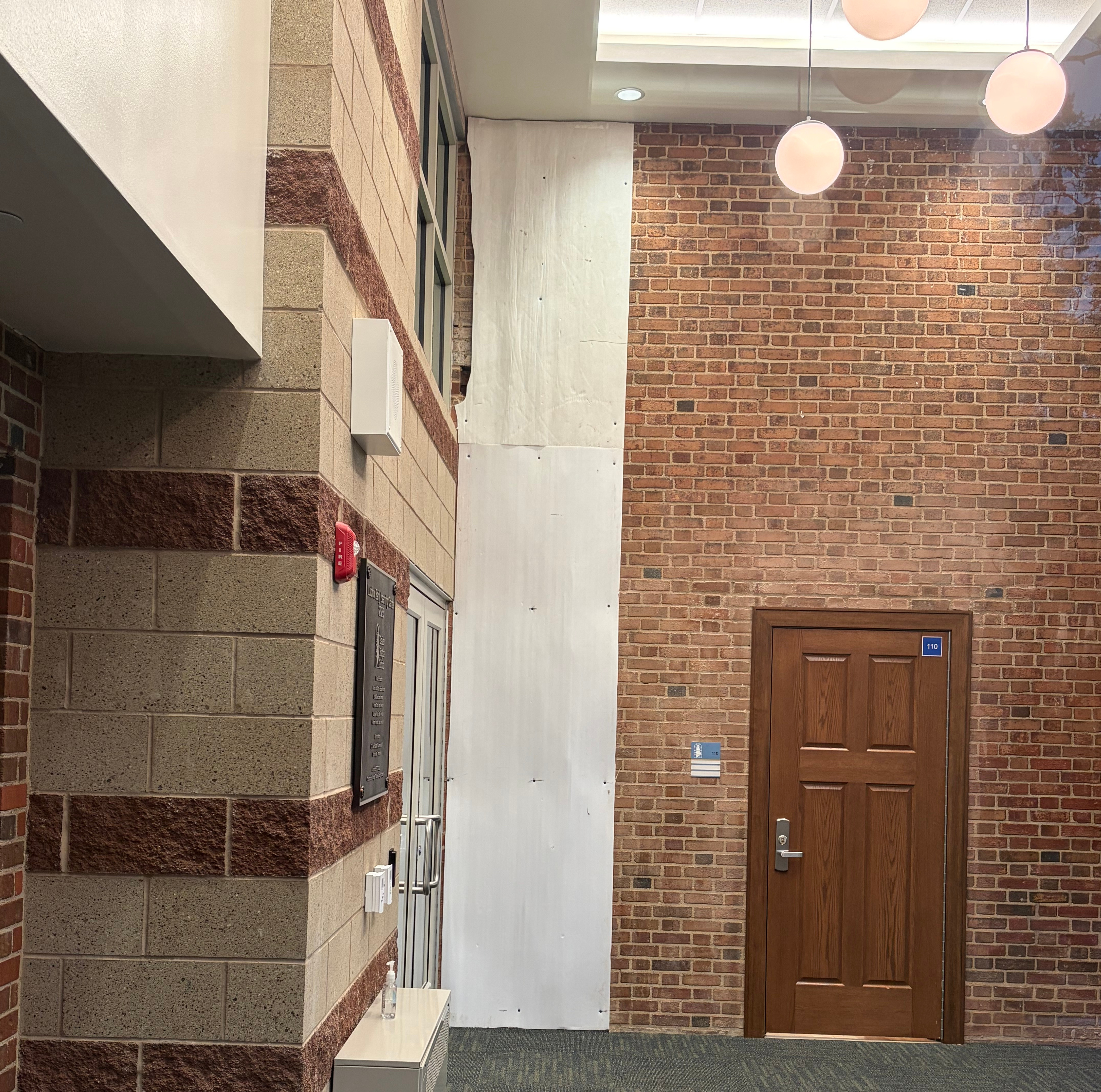 A large sheet of cardboard remains screwed into the full height of the wall in Ludlow Pre-K's newly constructed vestibule , covering up unknown damage that has yet to be repaired since the building opened in September 2025.