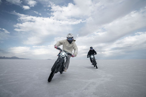 Pair of NIU XQi3 electric dirt bikes riding on a salt flat