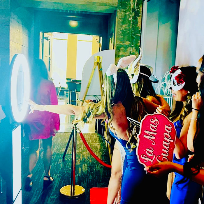 Guests celebrating in a luxury photo booth rental with golden backdrops.