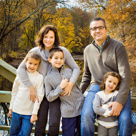 Family portrait: parents and three children on bridge, autumn background