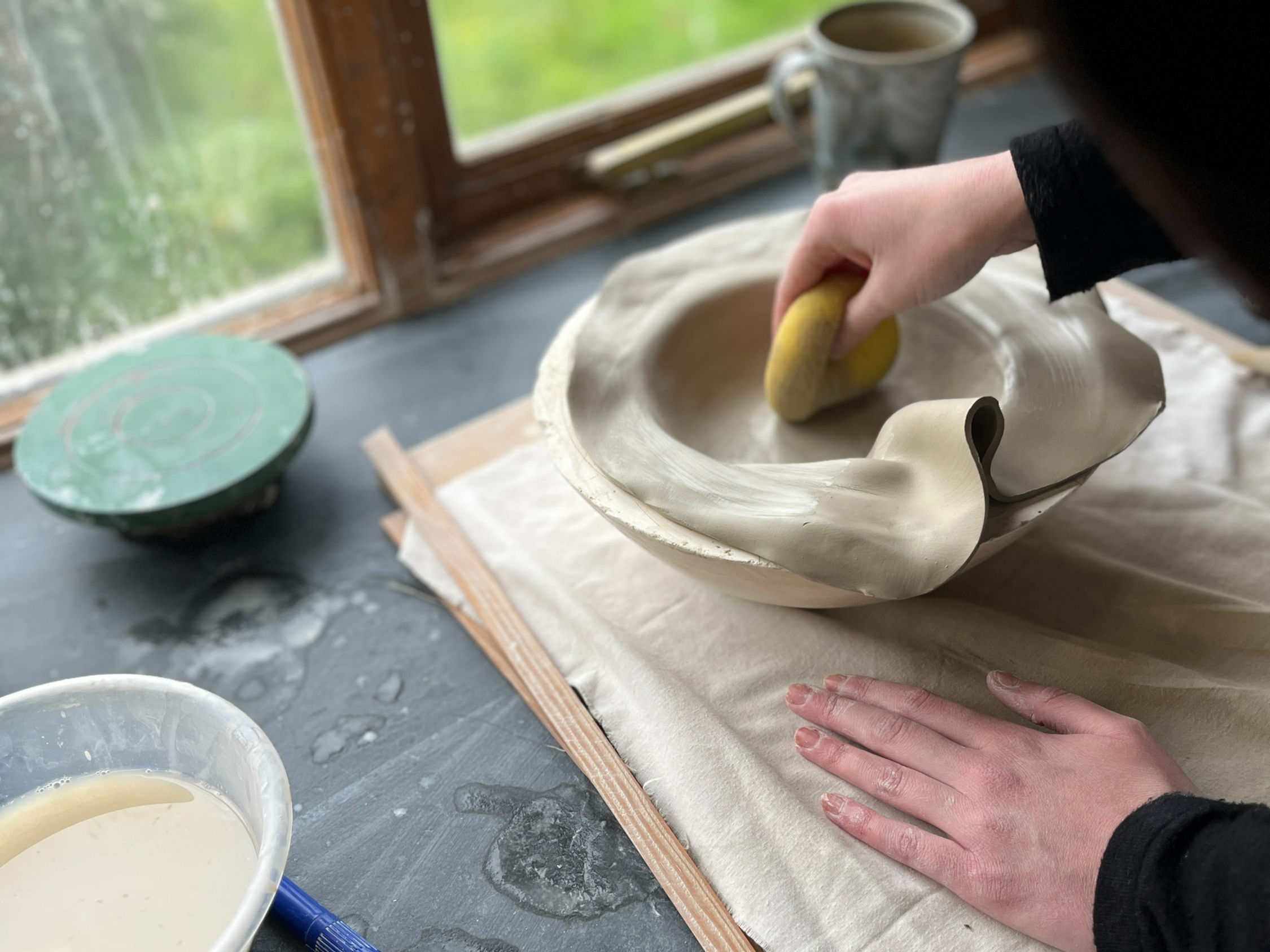 This image shows a group of women working outside creating pottery