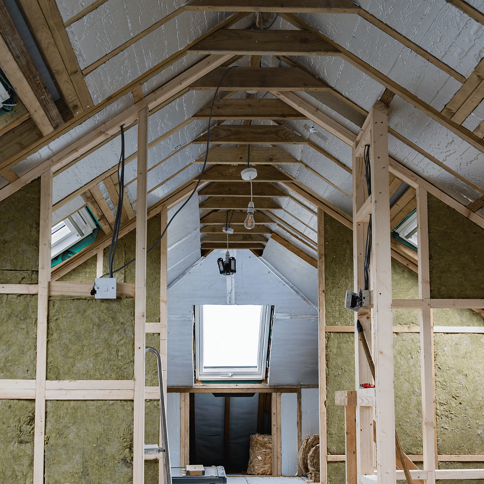 Unfinished attic with exposed wooden beams and insulation. A central skylight illuminates the space. Wires hang from the ceiling.
