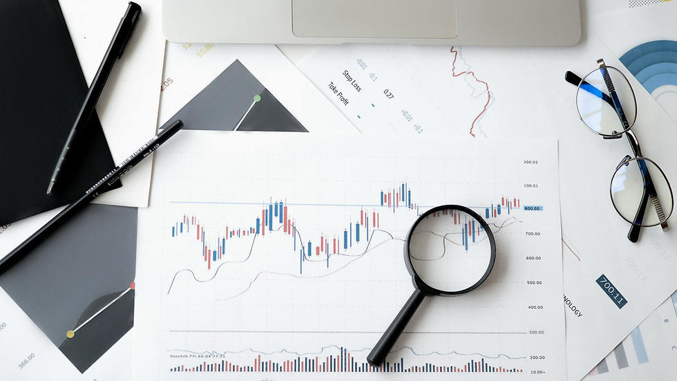 Flat lay of stock market analysis documents with magnifying glass, pens, and glasses.