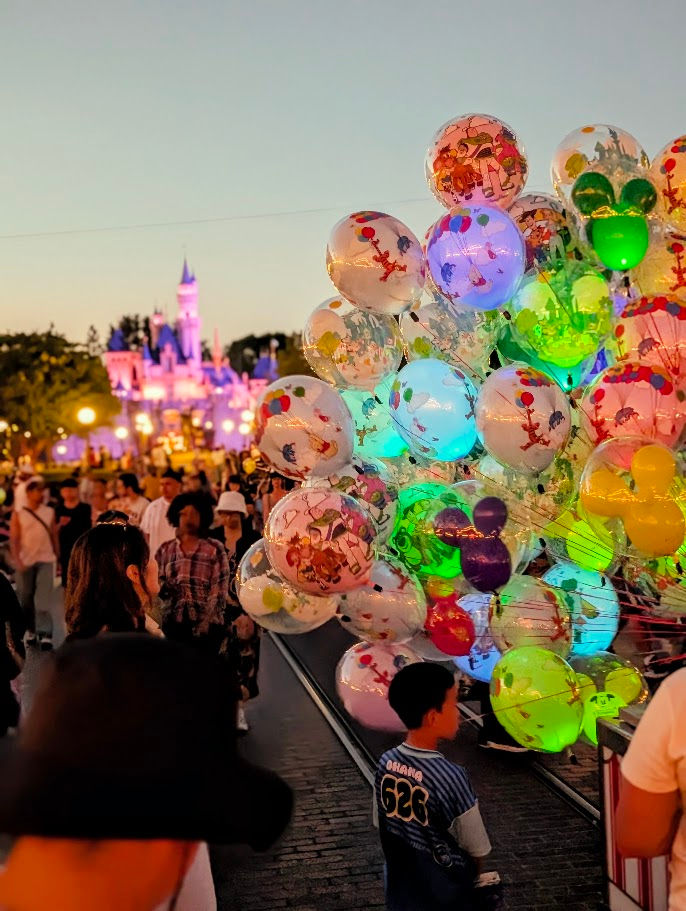 Colorful illuminated Disney balloons on Main Street USA with Sleeping Beauty Castle in the background
