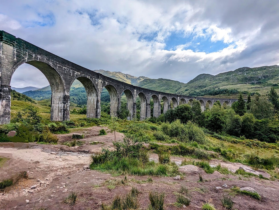 Glenfinnan Viaduct curving through green mountains in the Scottish Highlands