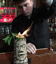 Mixologist serving a flaming tiki drink