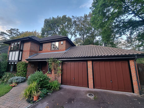 Tiled roof brick garage with integrated door surrounded by suburban greenery