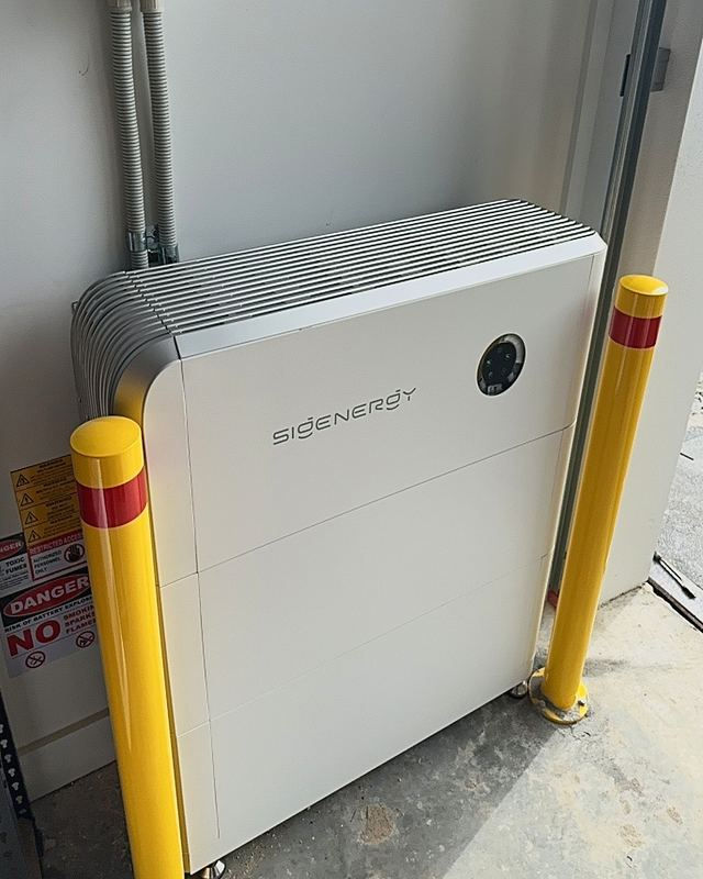 Home battery installed in a garage with yellow safety bollards