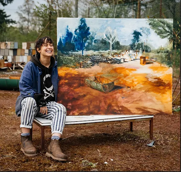 Marina Renee-Cemmick sitting on a bench with her painting at Colstoun House