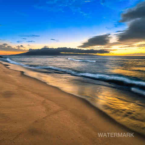 Photo containing image of the beach, waves, and hotel in the distance at sunset.