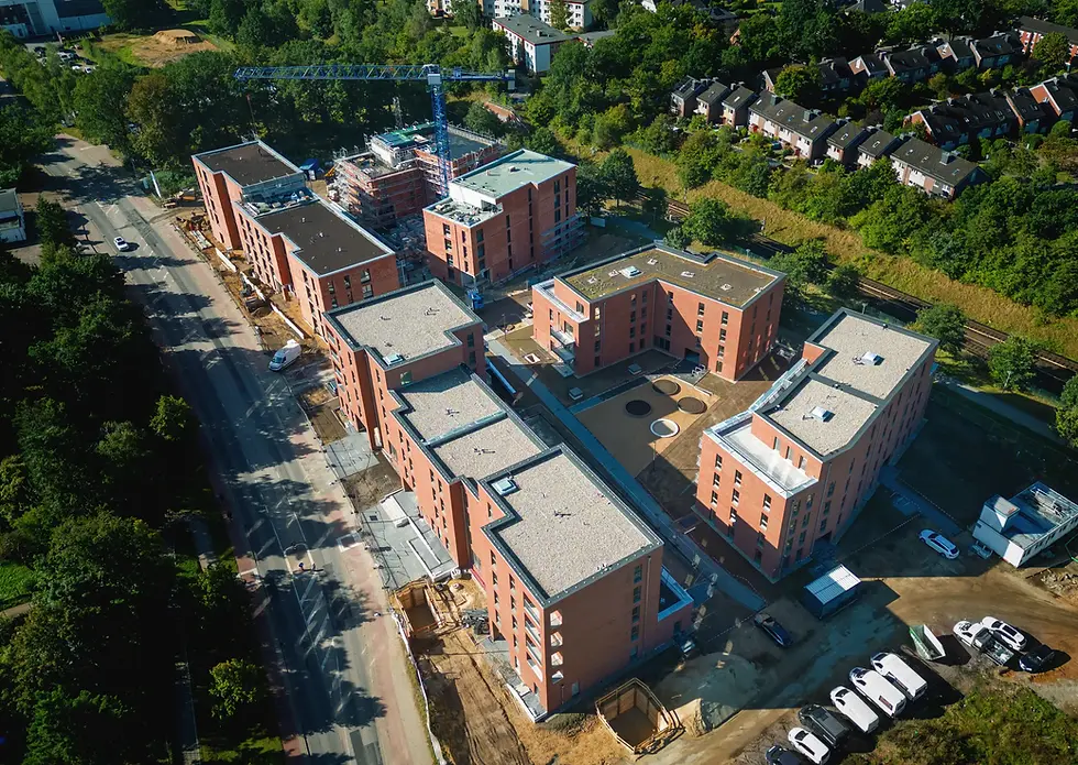Luftaufnahme eines Neubau-Wohnquartiers mit roten Backsteinhäusern und Innenhöfen.