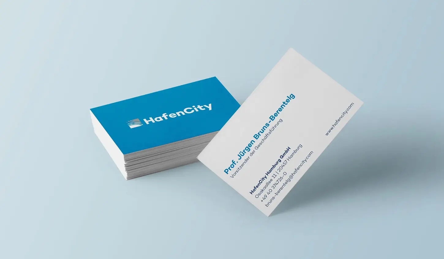 A stack of blue HafenCity business cards next to a white contact card on a light blue background.