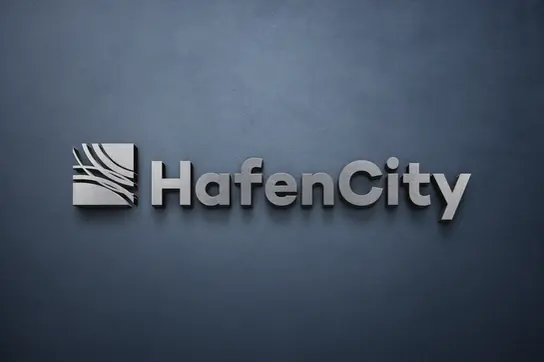3D brushed metal HafenCity logo mounted on a dark, textured gray wall. 