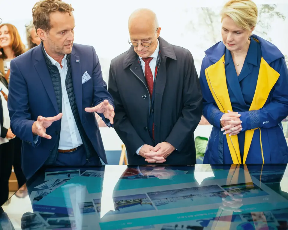 A man and a woman in business attire looking at a large interactive touchscreen table at an exhibition. 