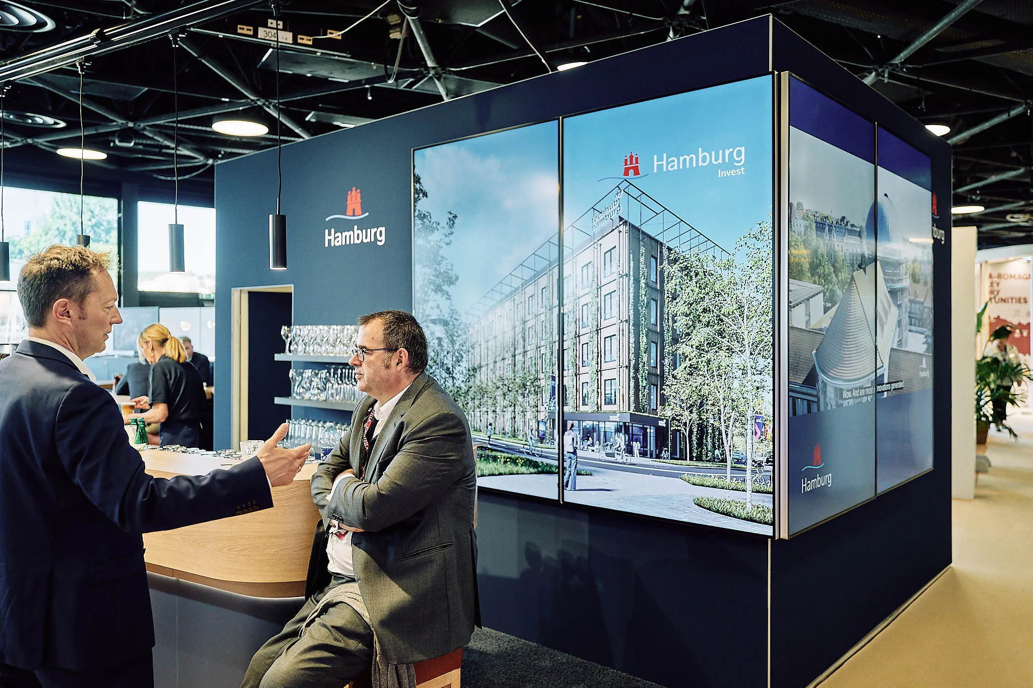 Large motion graphics display at a Hamburg trade show booth.