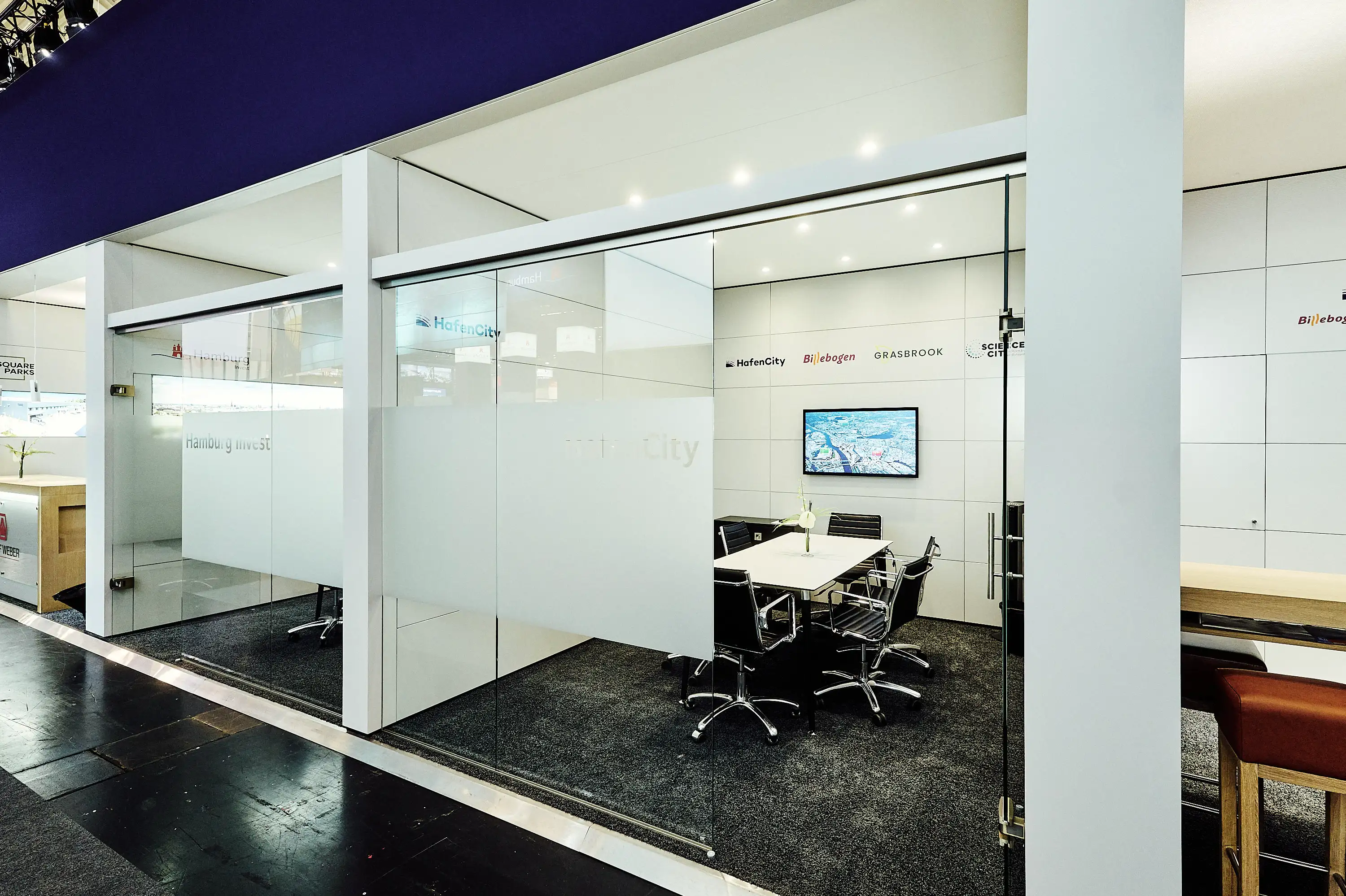 Modern glass meeting room booth with motion graphics screen.